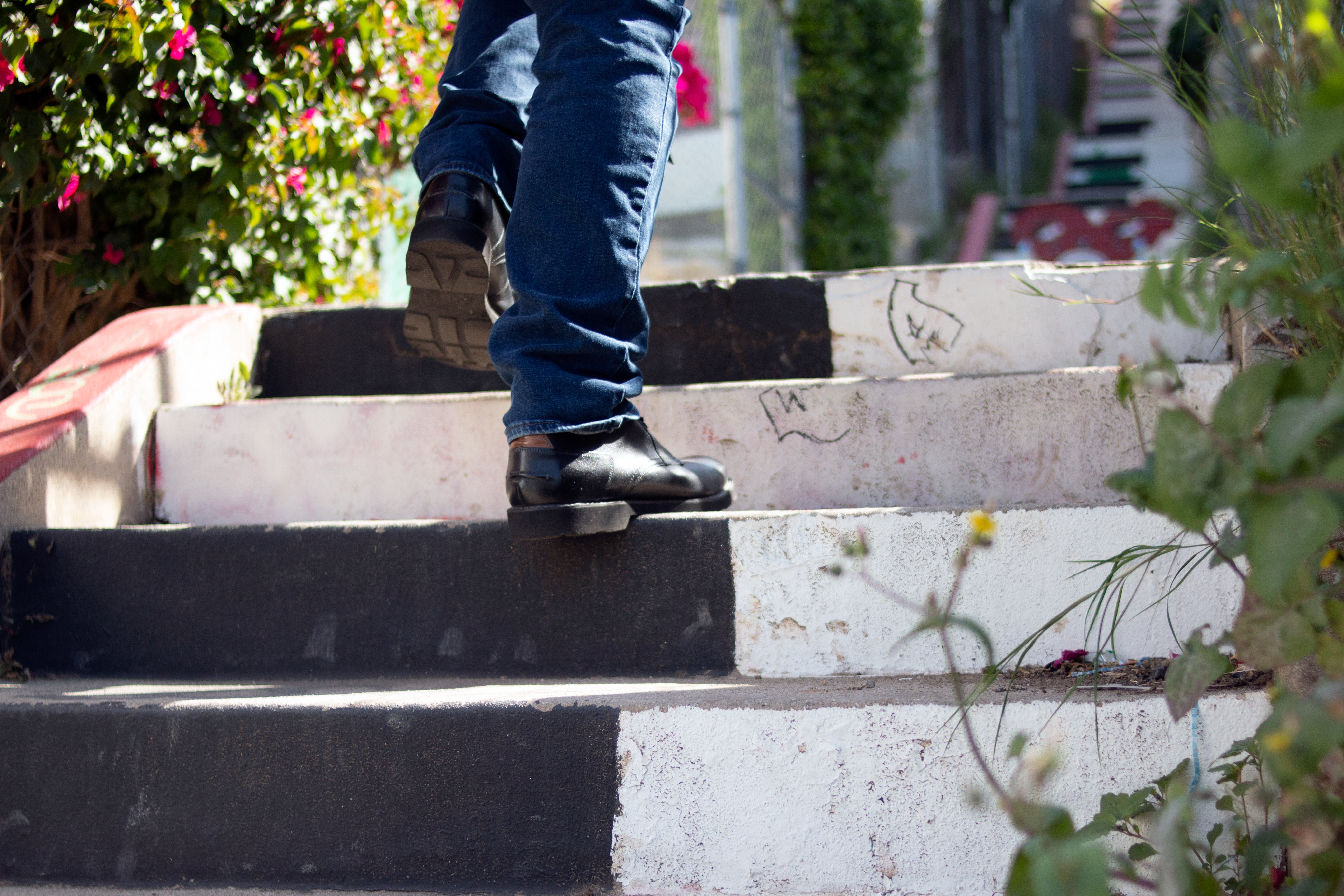 Legs in black boots and jeans climb a painted staircase.